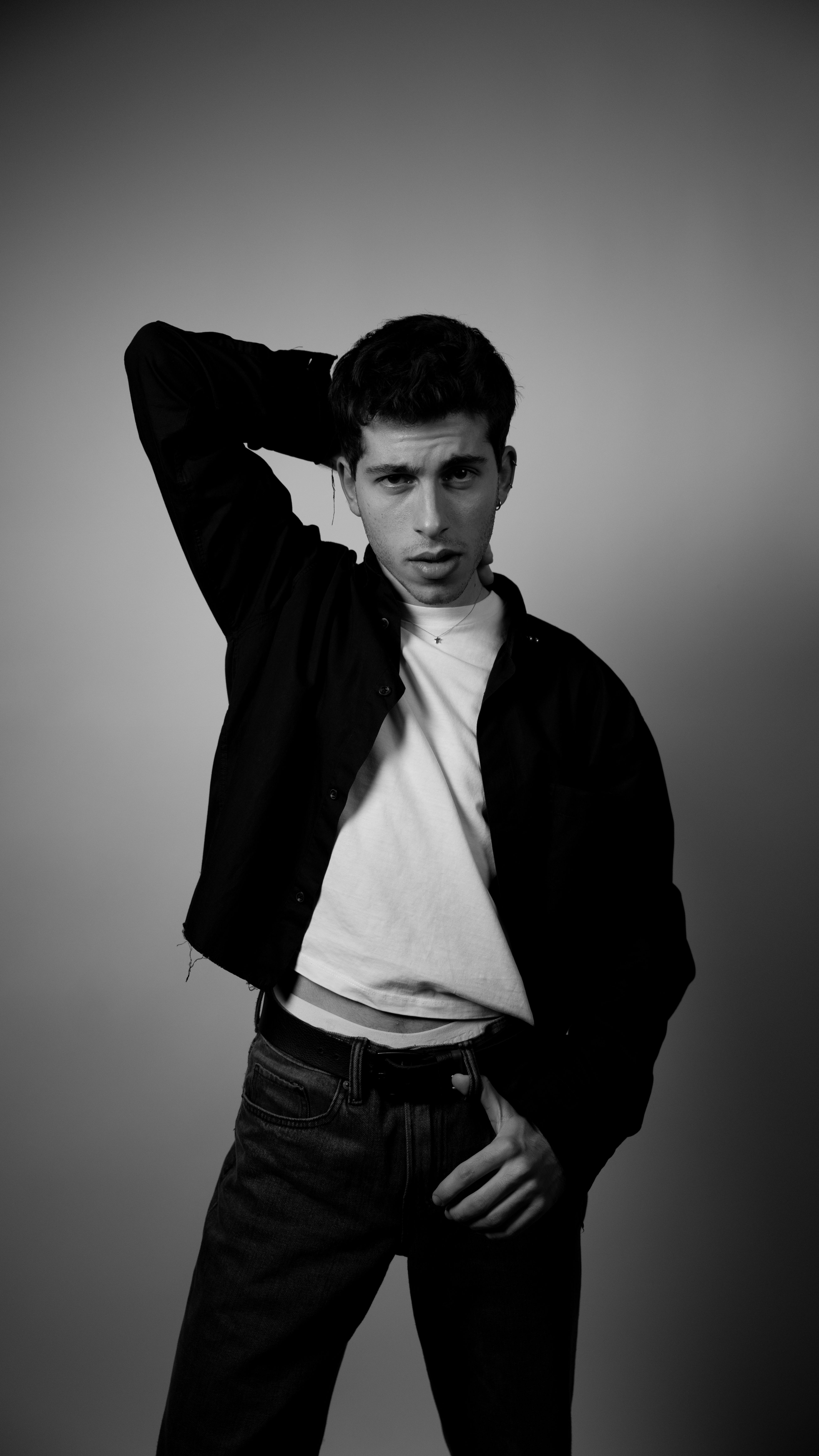 Artistic black and white portrait of a young man posing in a photo studio.