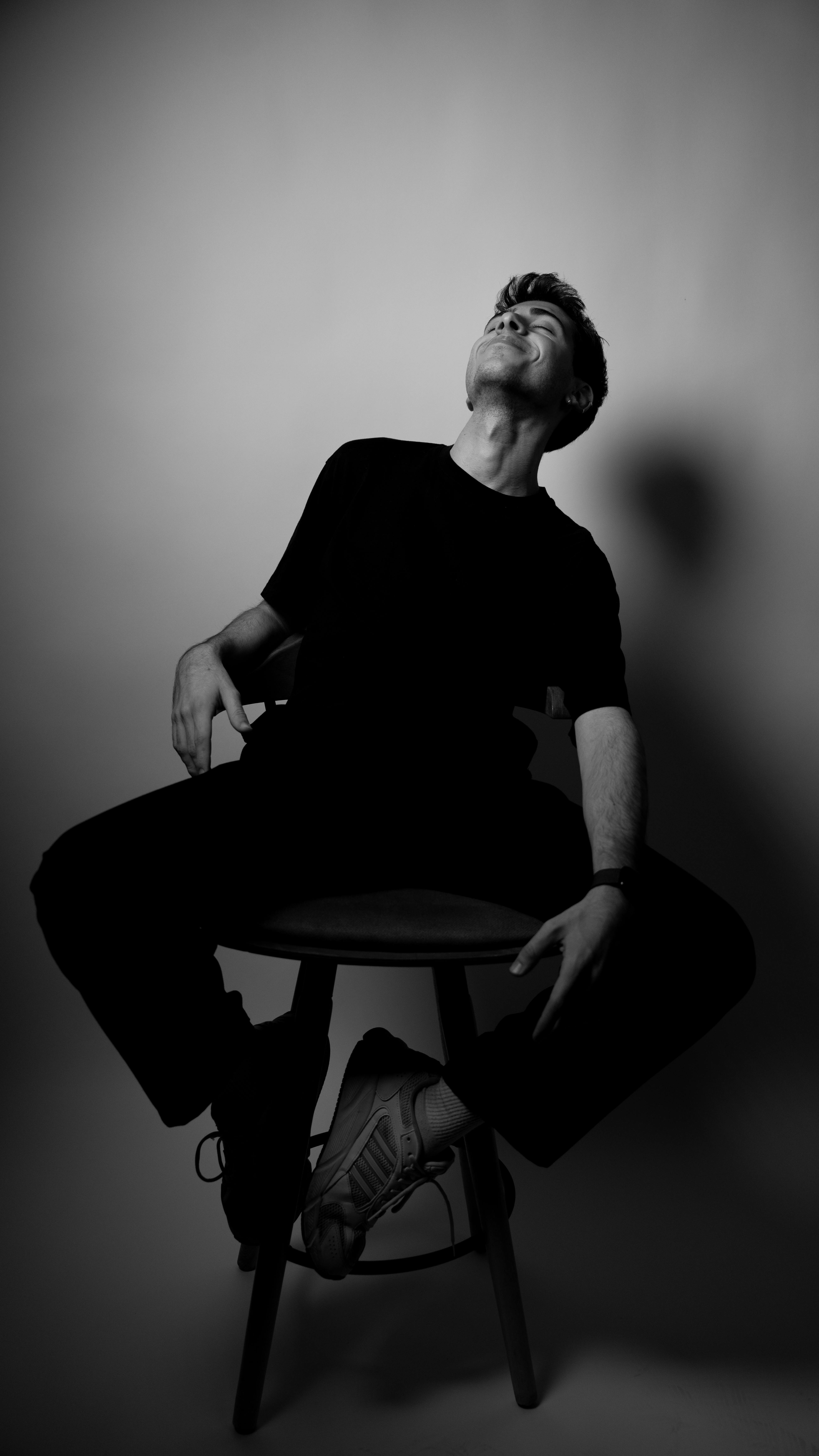 無料 椅子に座って内省を表現する男性の白黒スタジオポートレート。 写真素材