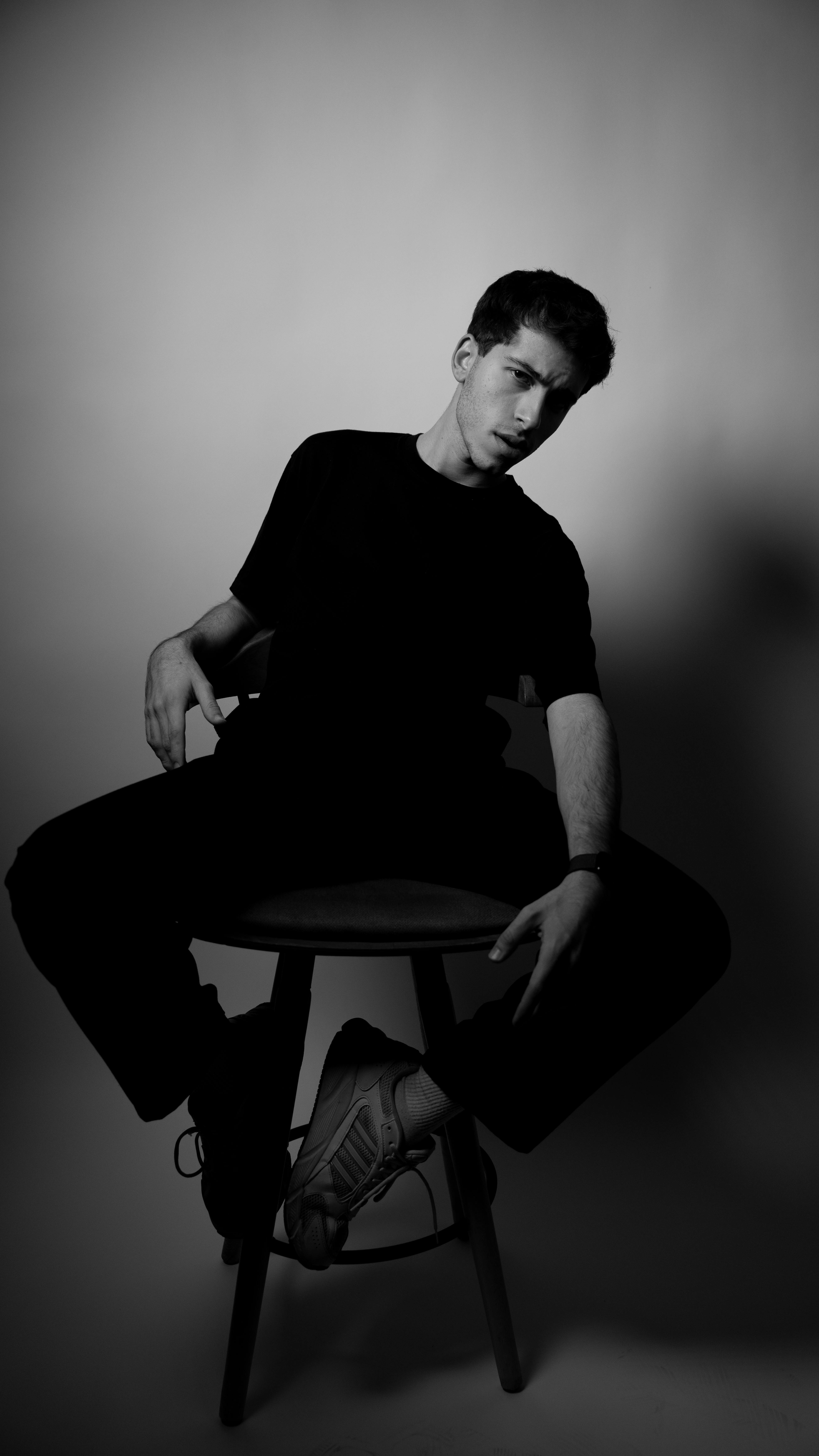 Безкоштовне Стилізований чорно-білий портрет чоловіка, що сидить у фотостудії, випромінюючи сучасні художні вібрації. стокове фото