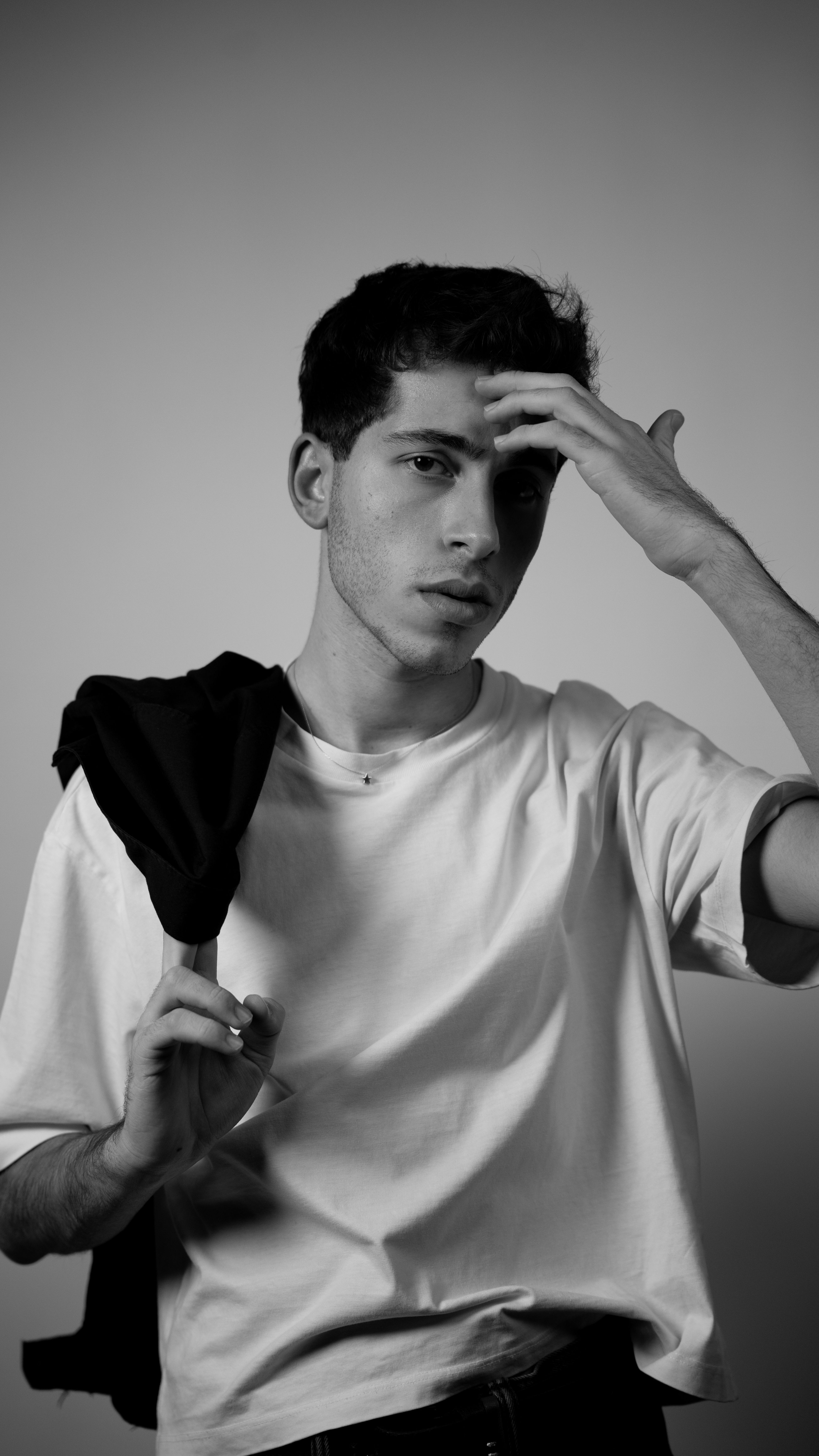 Captivating black and white portrait featuring a young man posing in a studio setting.