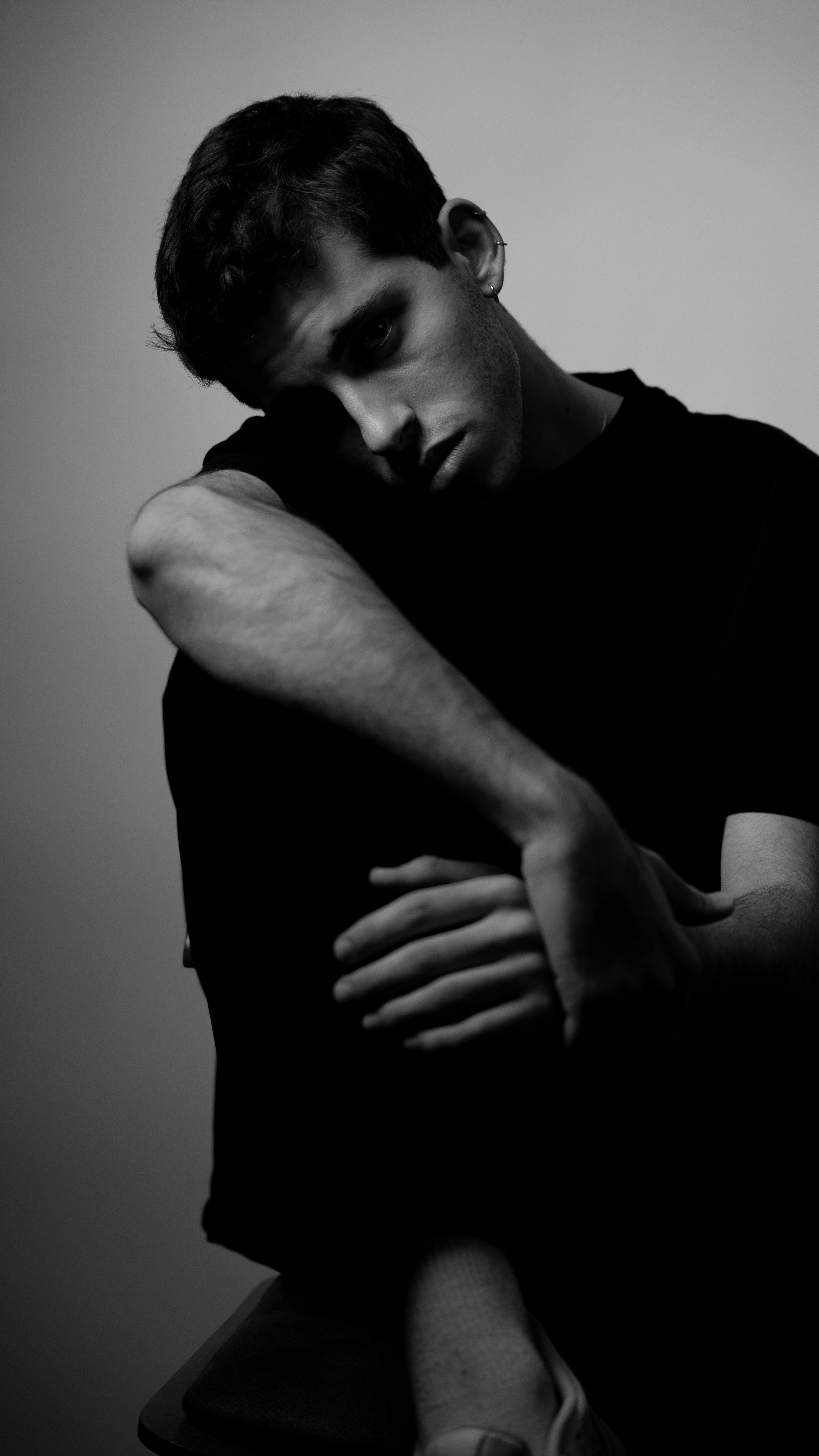 gratis Expressief zwart-witportret van een jonge man in een peinzende houding, waarin emotie centraal staat. Stockfoto