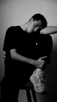Black and white portrait of a young man in a contemplative pose, studio setting.