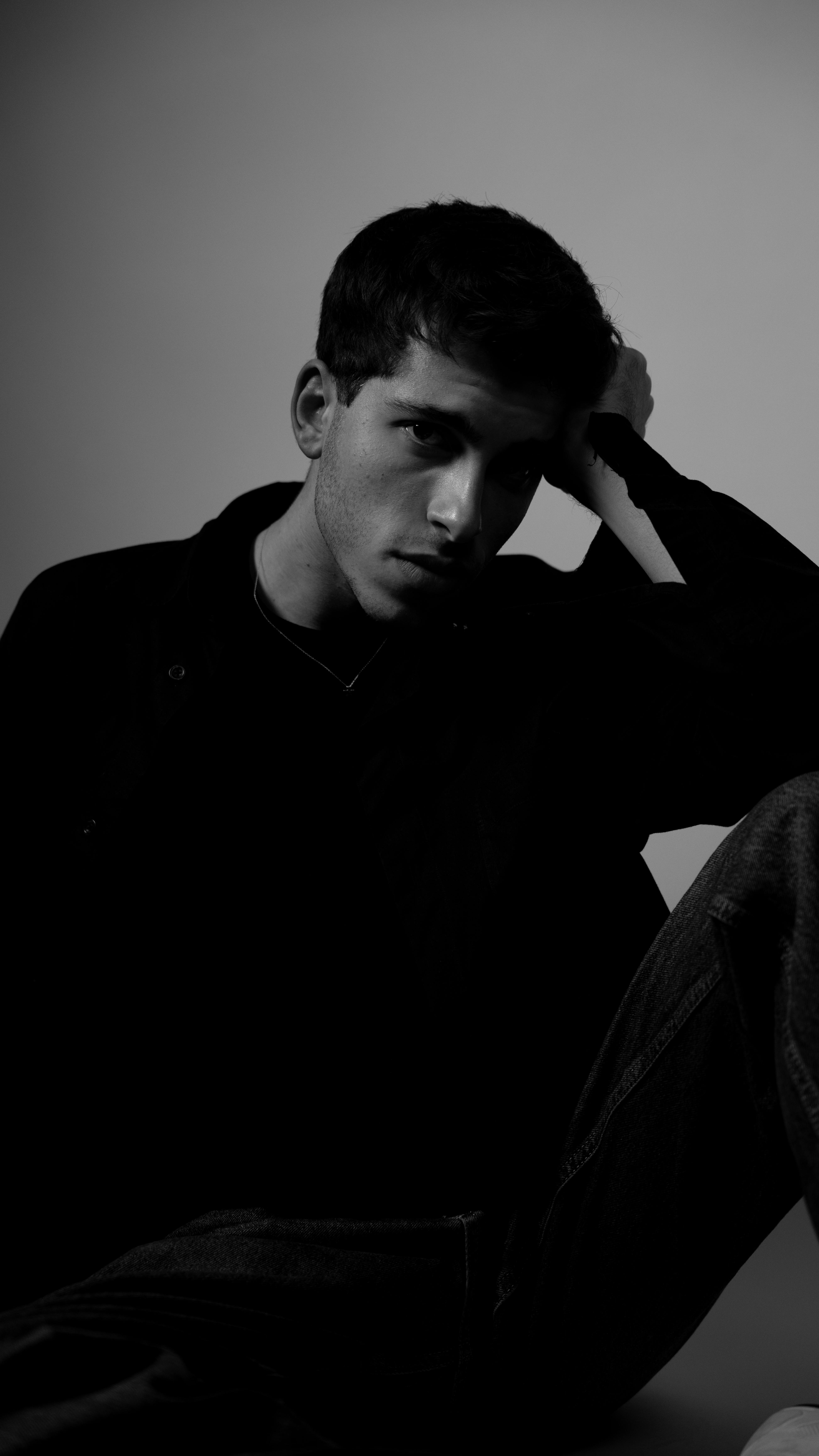 Moody black and white portrait of a male in a studio setting, showcasing deep contrast and introspection.