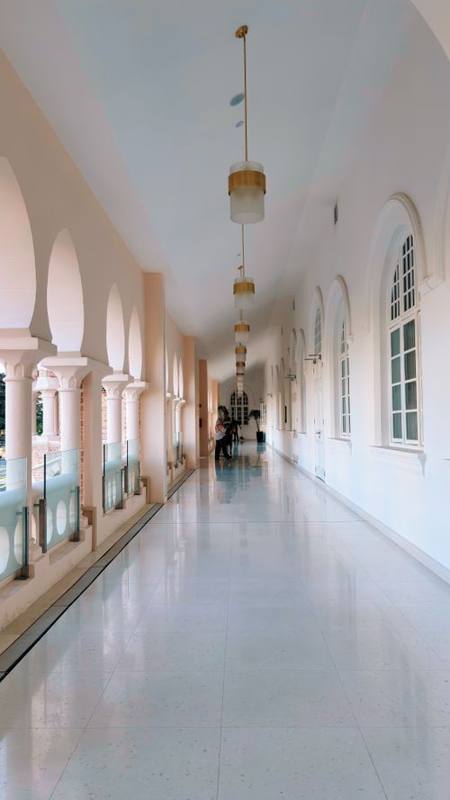 Free A serene colonial-style hallway in Kuala Lumpur, Malaysia with arches and chandeliers. Stock Photo