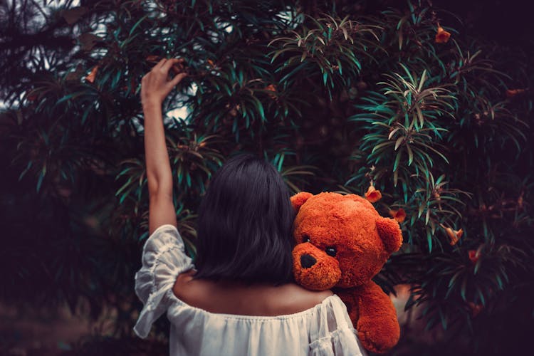 Back View Of A Woman Carrying Her Teddy Bear