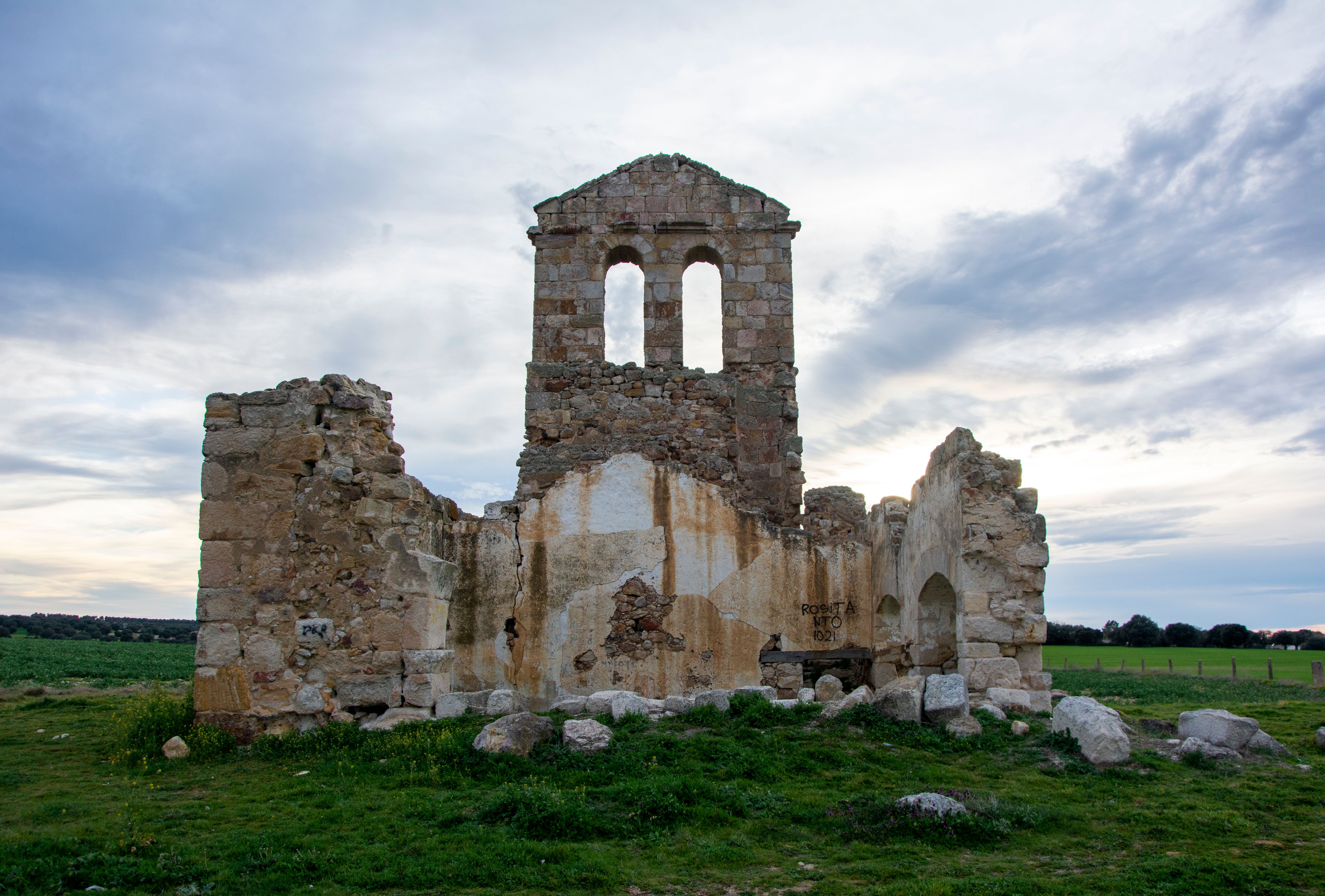 Historical stone ruins under a vast, dramatic sky, suggesting an ancient or medieval period.