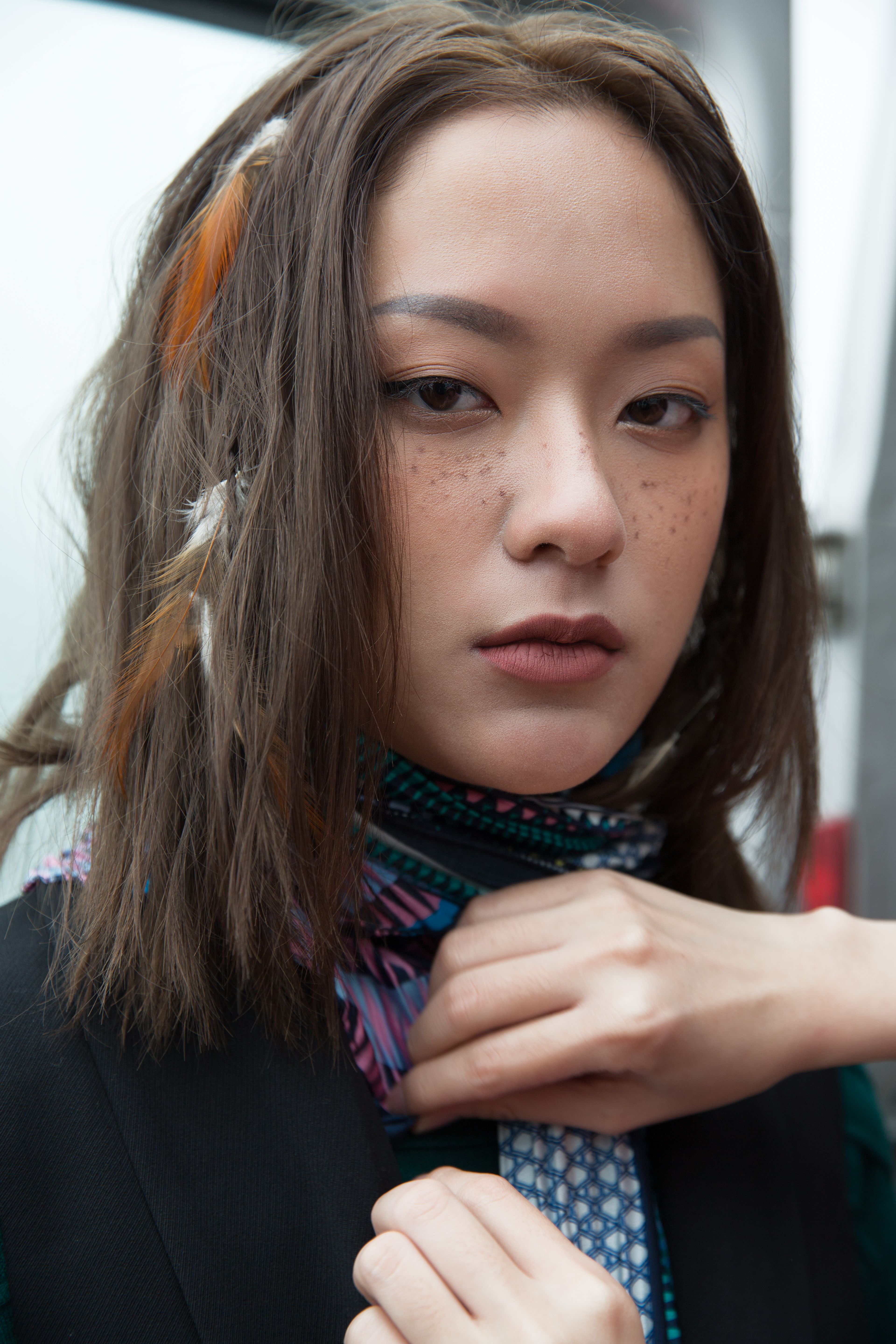 Close-up of a trendy woman with unique hairstyle and scarf, showcasing modern fashion.