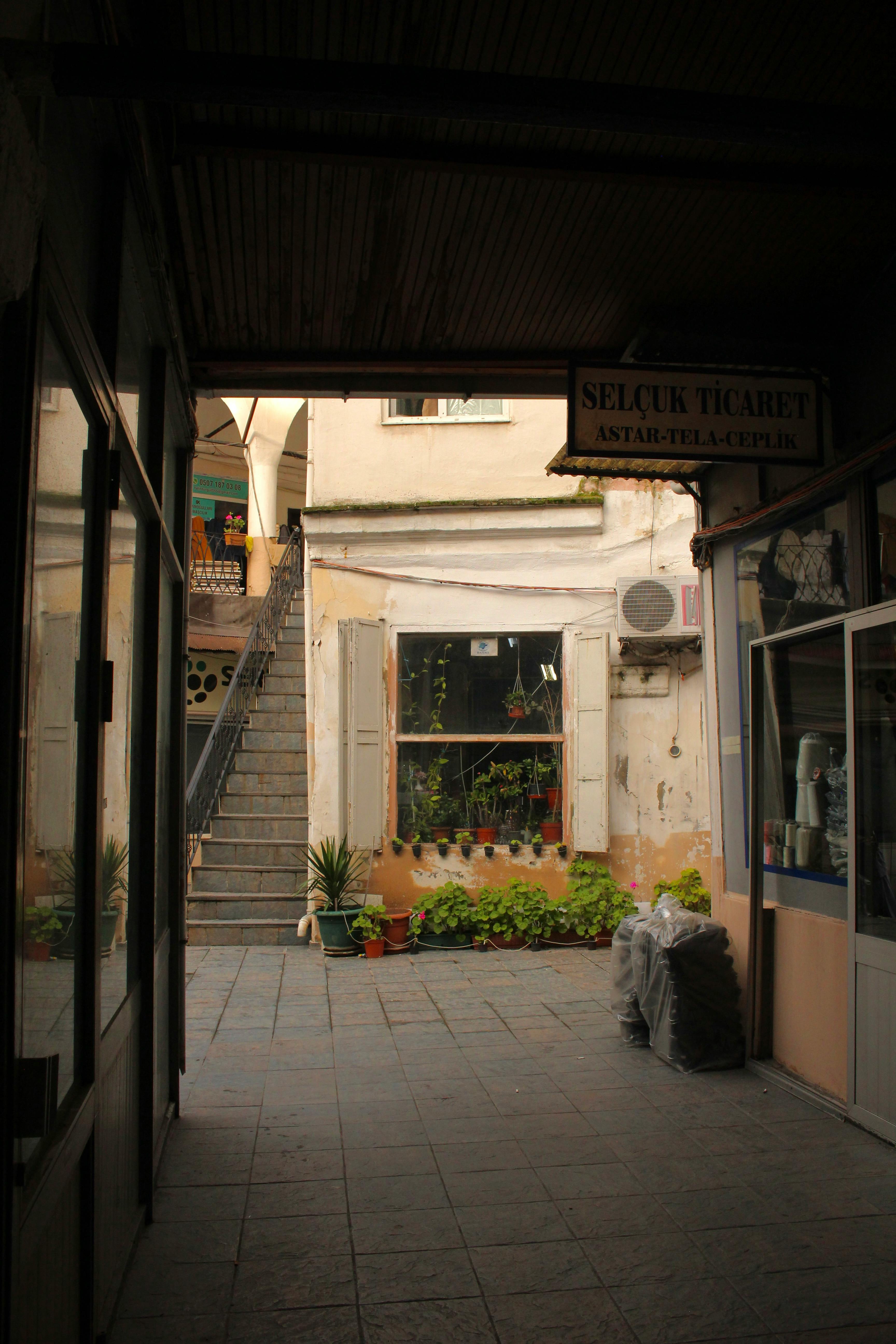 Kostenlos Entdecken Sie eine malerische Gasse in einem türkischen Basar mit nostalgischem Charme und üppiger Pflanzenpracht. Stock-Foto
