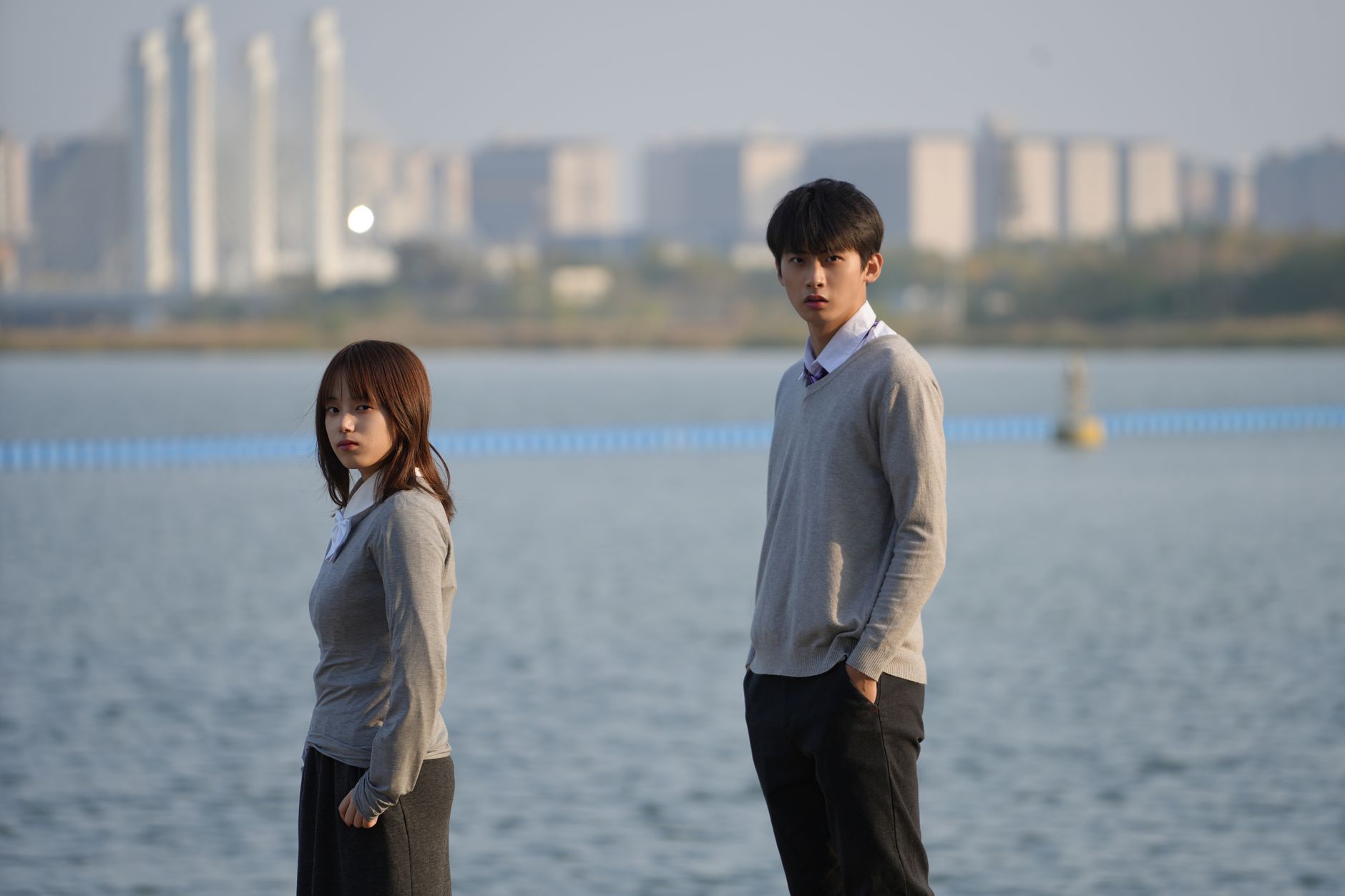 Young couple standing by a waterfront with cityscape in Zhengzhou, China.