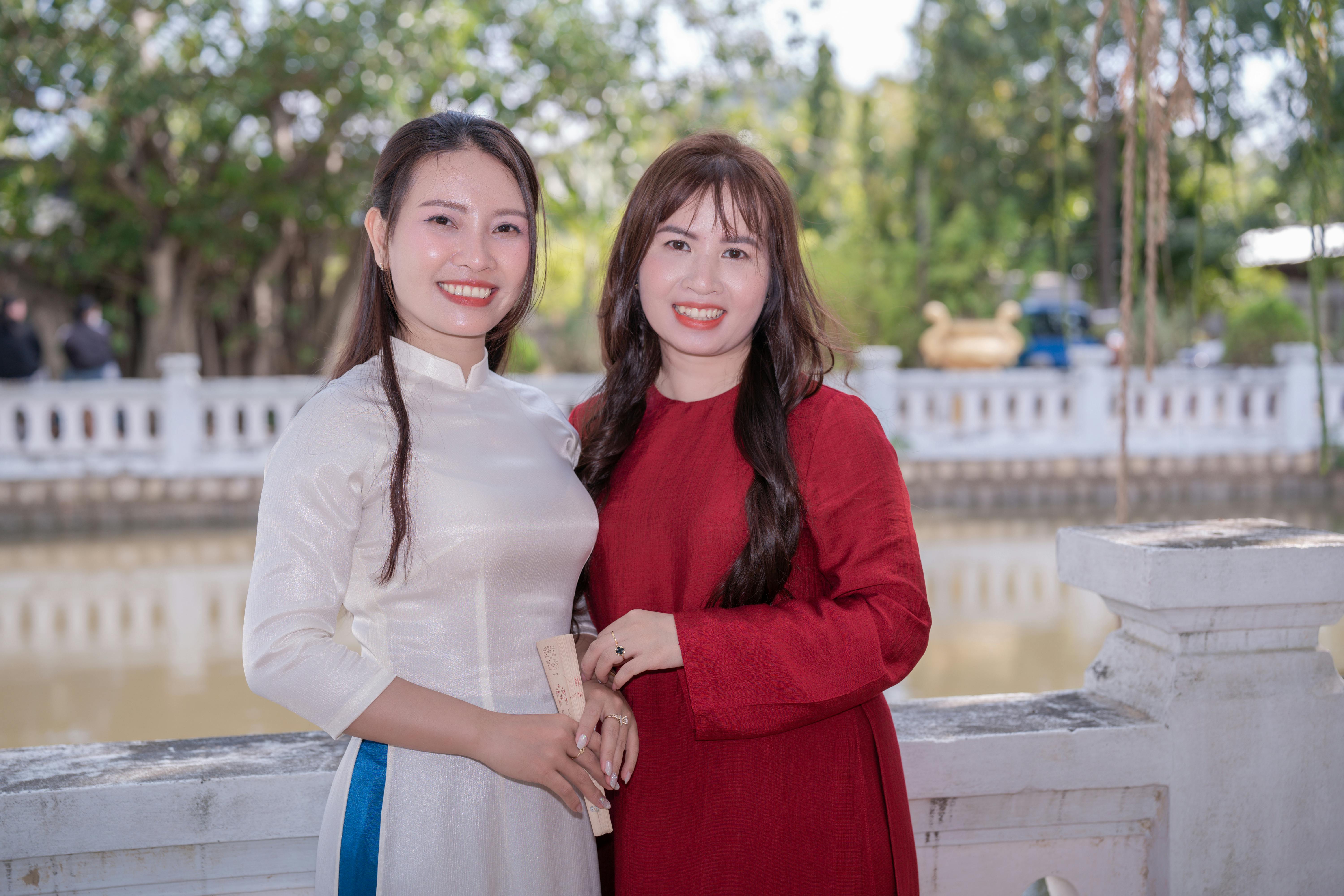 Gratis Due donne in abiti tradizionali vietnamiti posano all'aperto con uno sfondo panoramico. Foto a disposizione