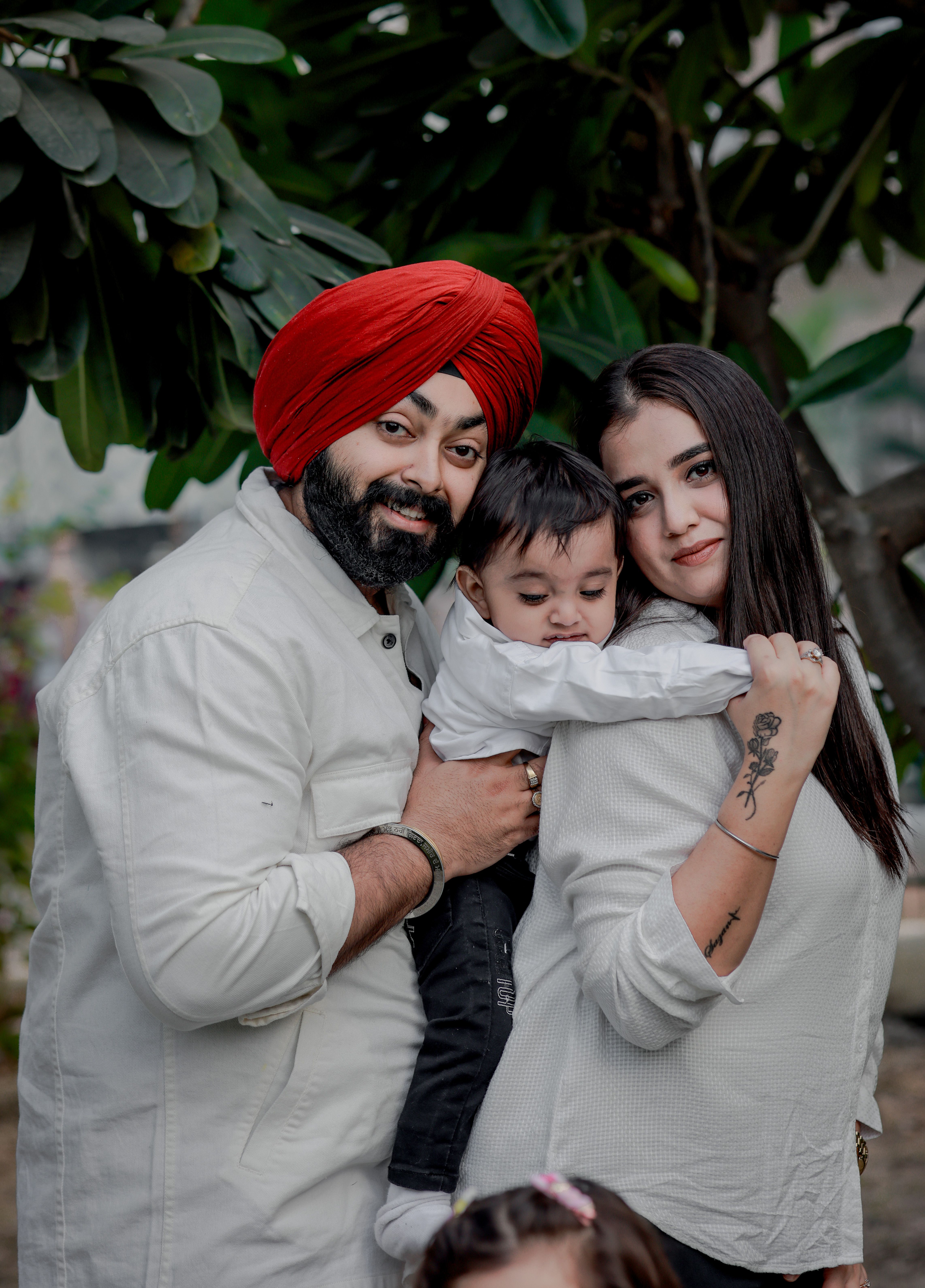 A joyful family portrait featuring parents and their baby outdoors, capturing love and togetherness.