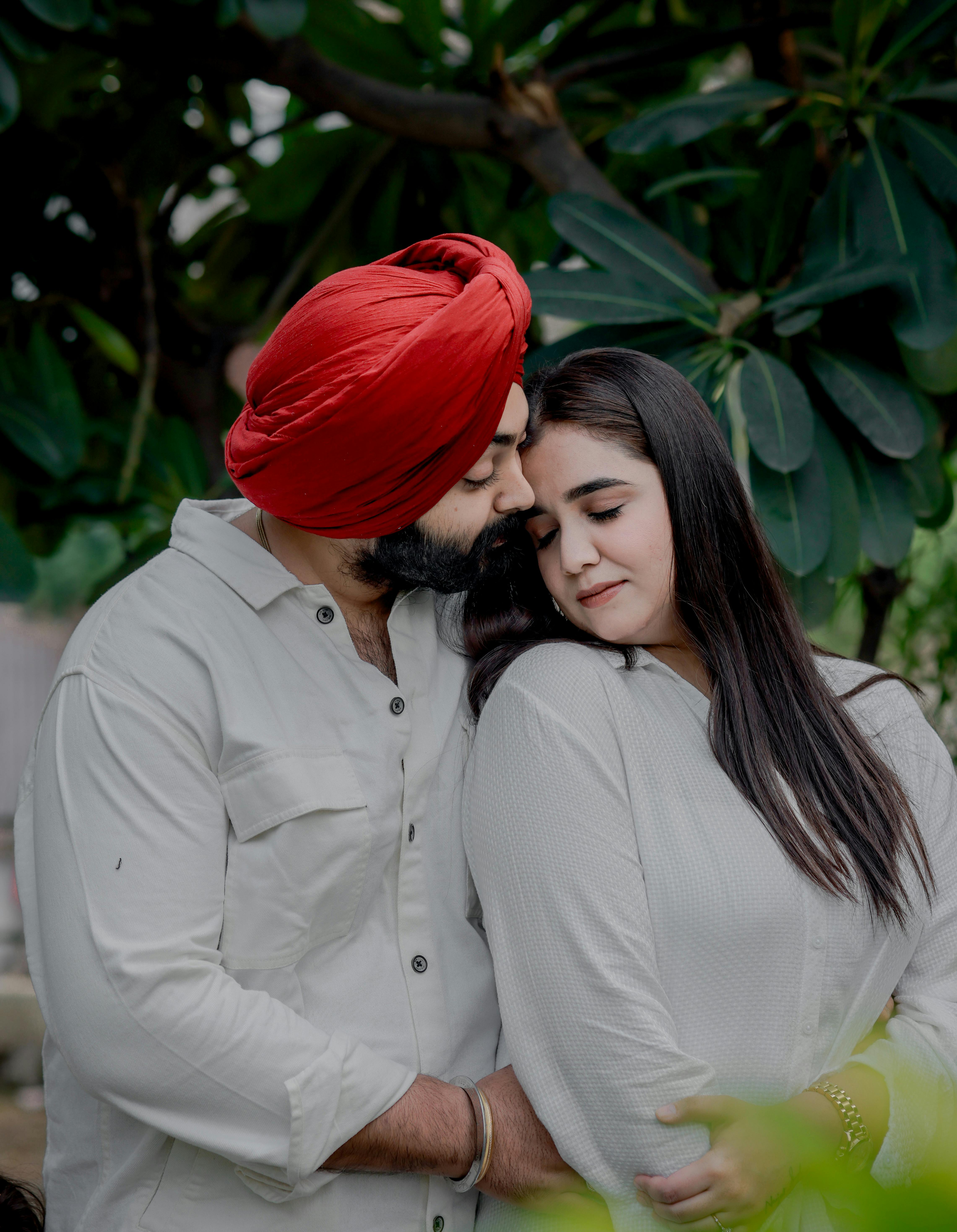 A loving South Asian couple sharing an intimate moment in a lush outdoor setting.