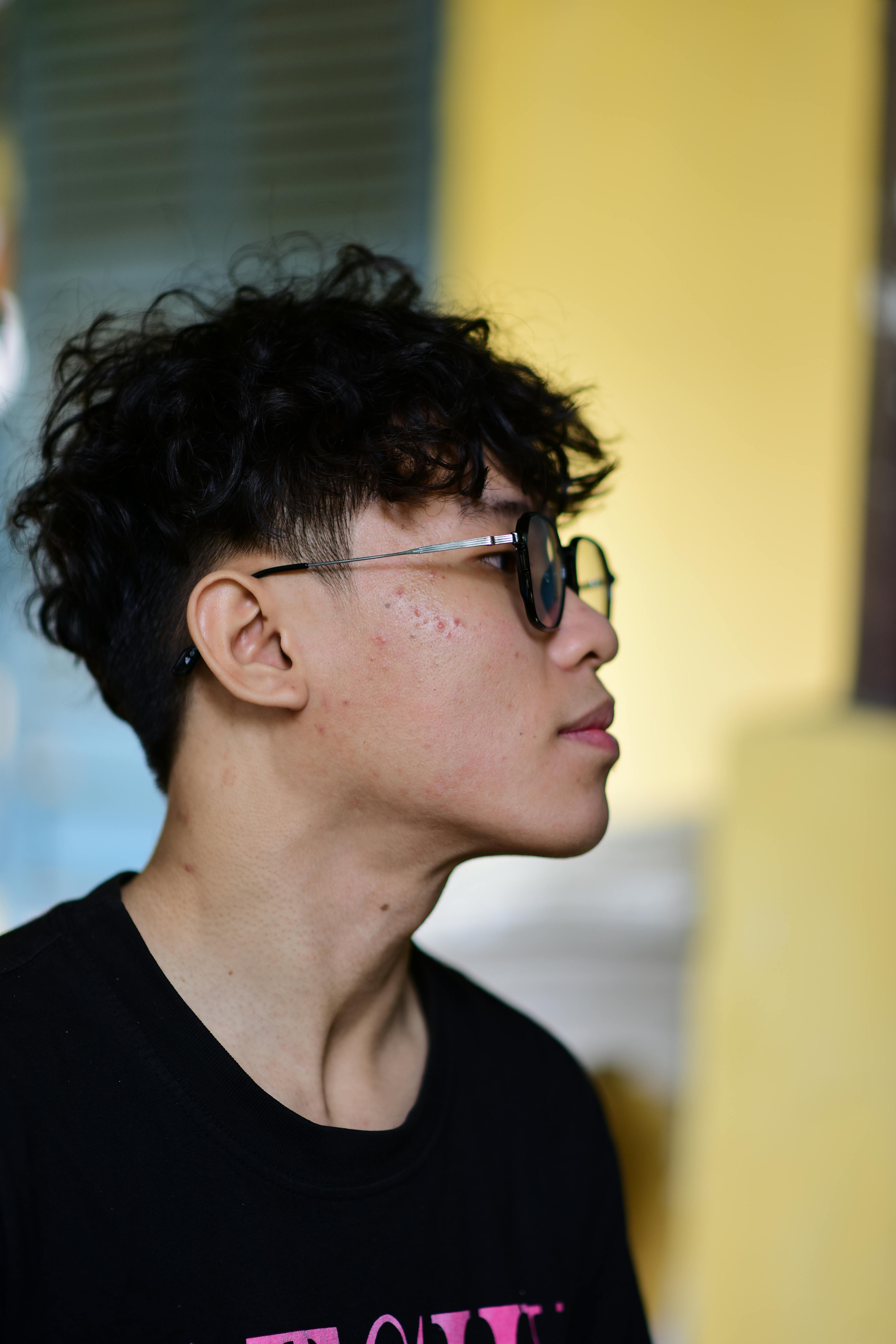 Side profile portrait of a teenager wearing sunglasses with a contemplative expression indoors.