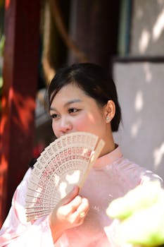Portrait of a woman in traditional dress with a decorative fan, enjoying a sunny moment.