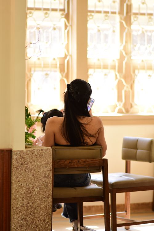 Free A woman seated on a chair indoors using her smartphone in a brightly lit room. Stock Photo