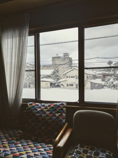 Free Interior with patterned chairs overlooking a snow-covered Toyooka street through a window. Stock Photo