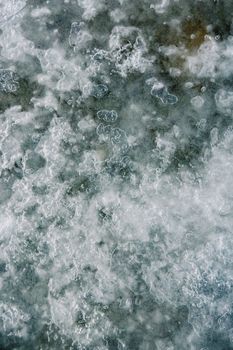 Close-up of ice and snow patterns forming a textured abstract art on a frozen surface in winter.