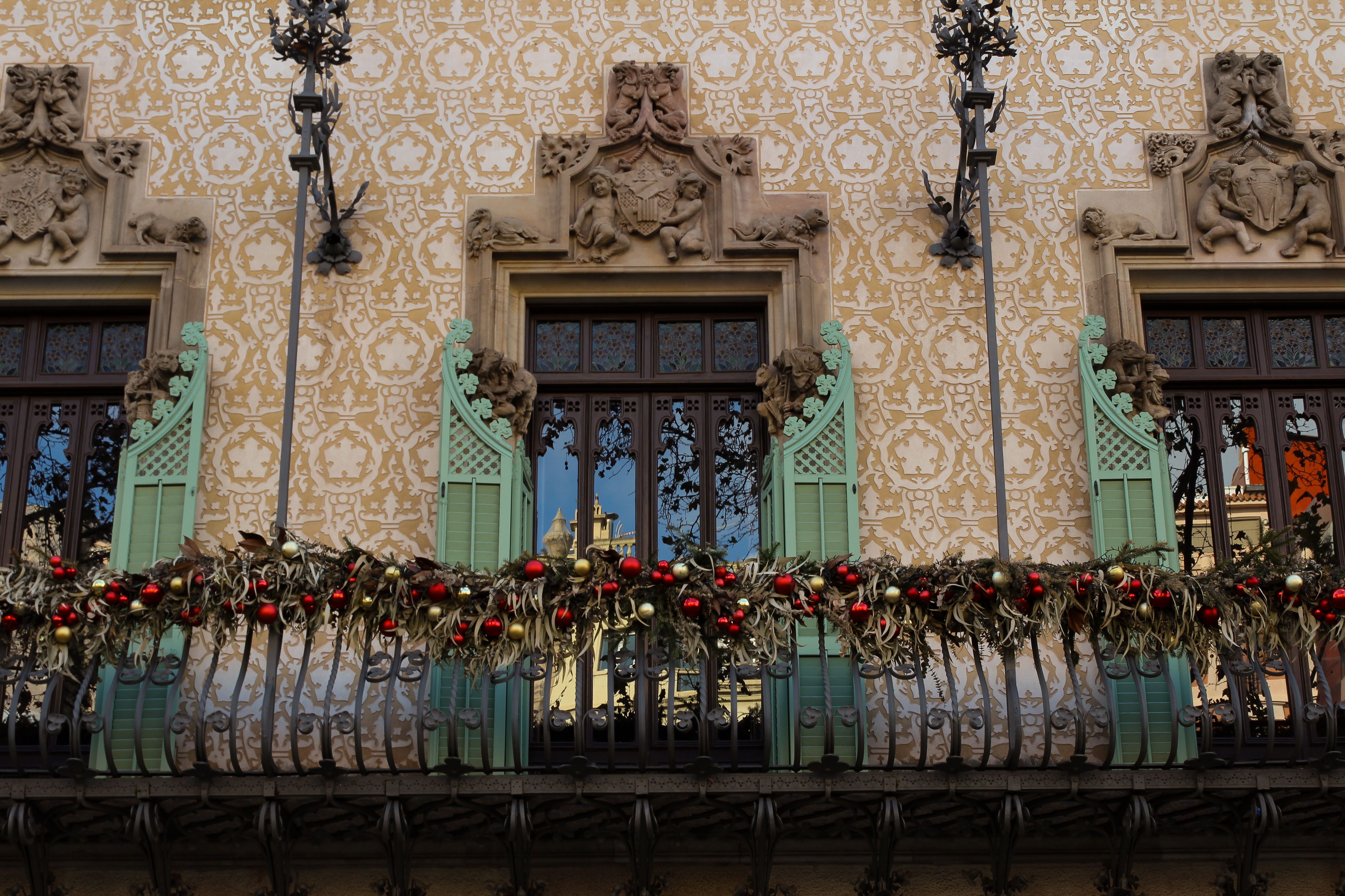Elegant building facade with intricate details and vibrant holiday garlands in urban setting.