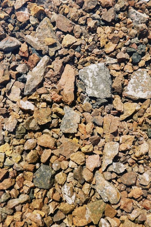 Free Close-up of a diverse gravel surface showcasing various rock sizes and textures under natural sunlight. Stock Photo