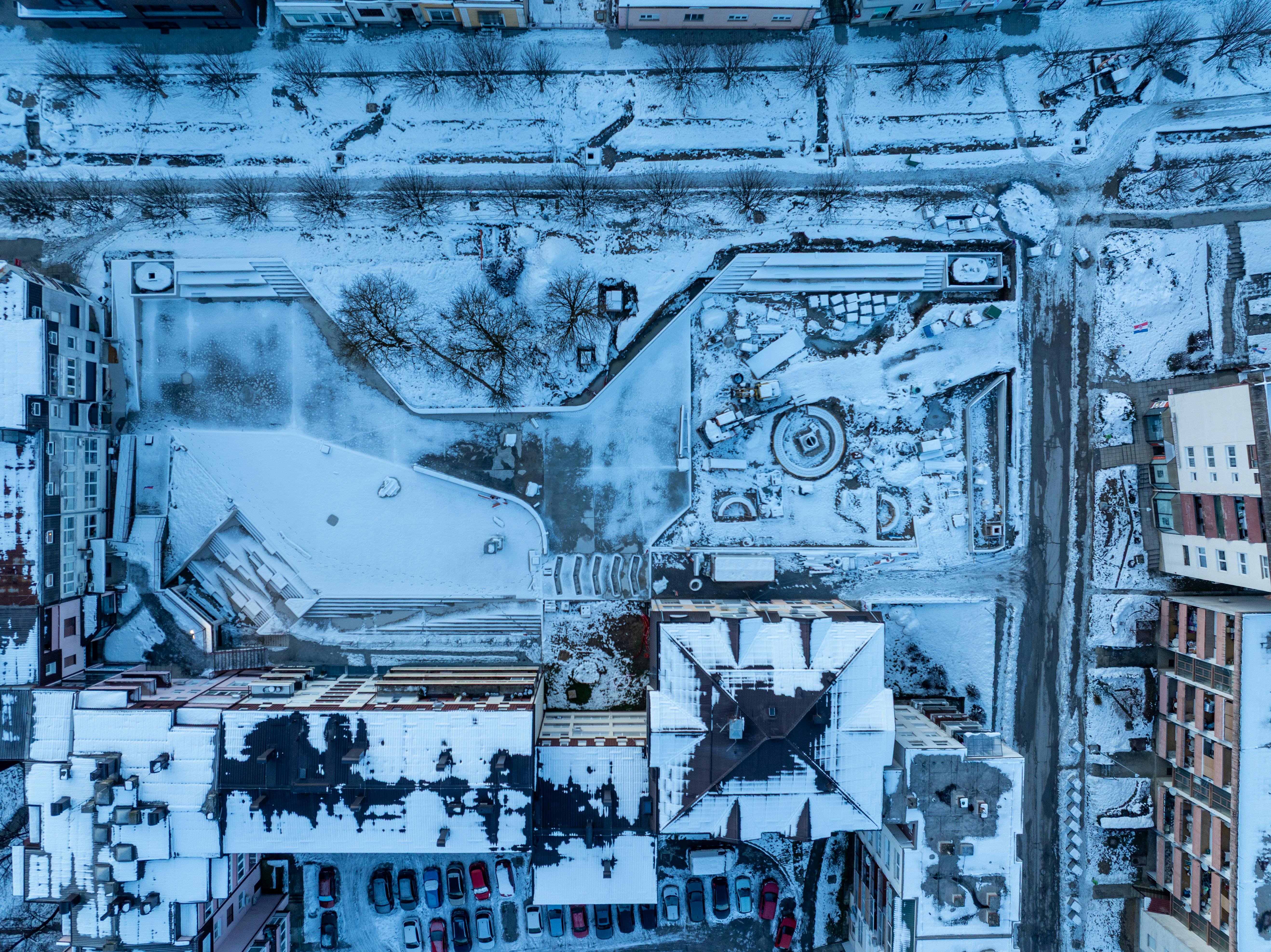bezplatná Letecký snímek shora dolů na zasněžené městské budovy a ulice v zimě, ukazující městskou architekturu. Základová fotografie