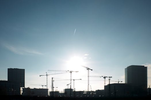 Silhouette of tower cranes and buildings under a bright sky in Hamburg, Germany.