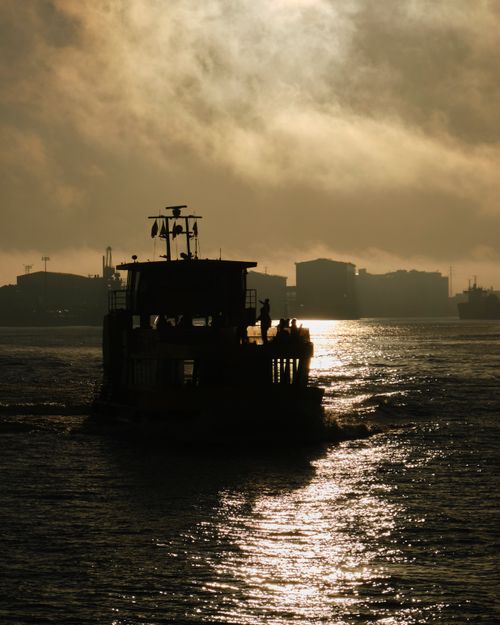 Free Silhouette of a ferry on the Elbe River during sunrise with dramatic clouds in Hamburg, Germany. Stock Photo