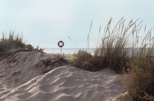Free Tranquil view of sand dunes and beach in Monte Gordo, Faro, Portugal, with a lifebuoy by the ocean. Stock Photo