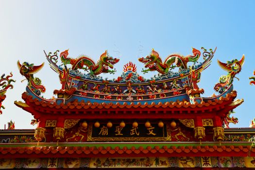 Intricate dragon-adorned roof of a traditional Taiwanese temple under a clear blue sky.