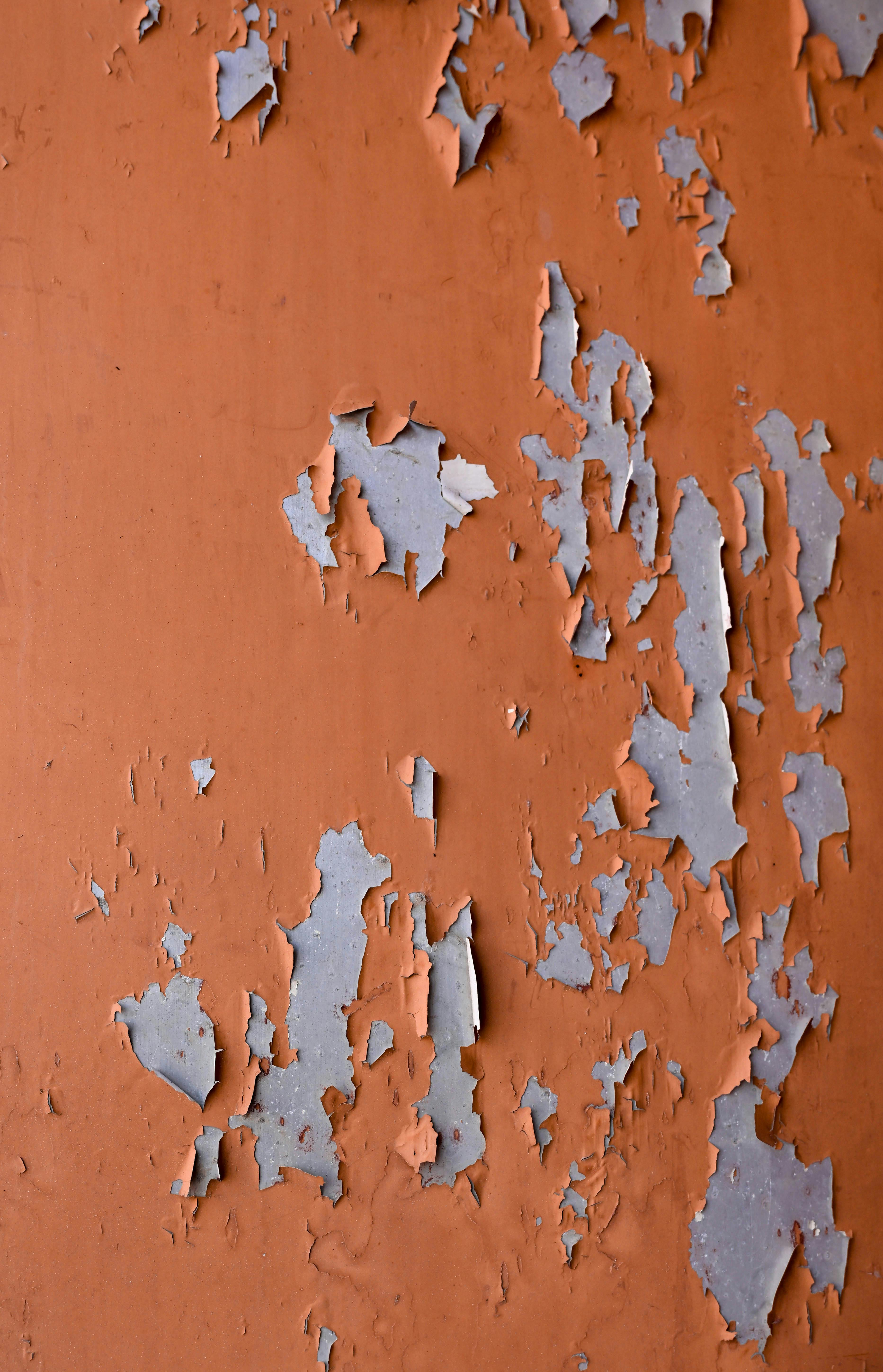Gratis Un primo piano artistico di una parete arancione rustica con vernice scrostata, che mette in mostra una texture di degrado urbano. Foto a disposizione
