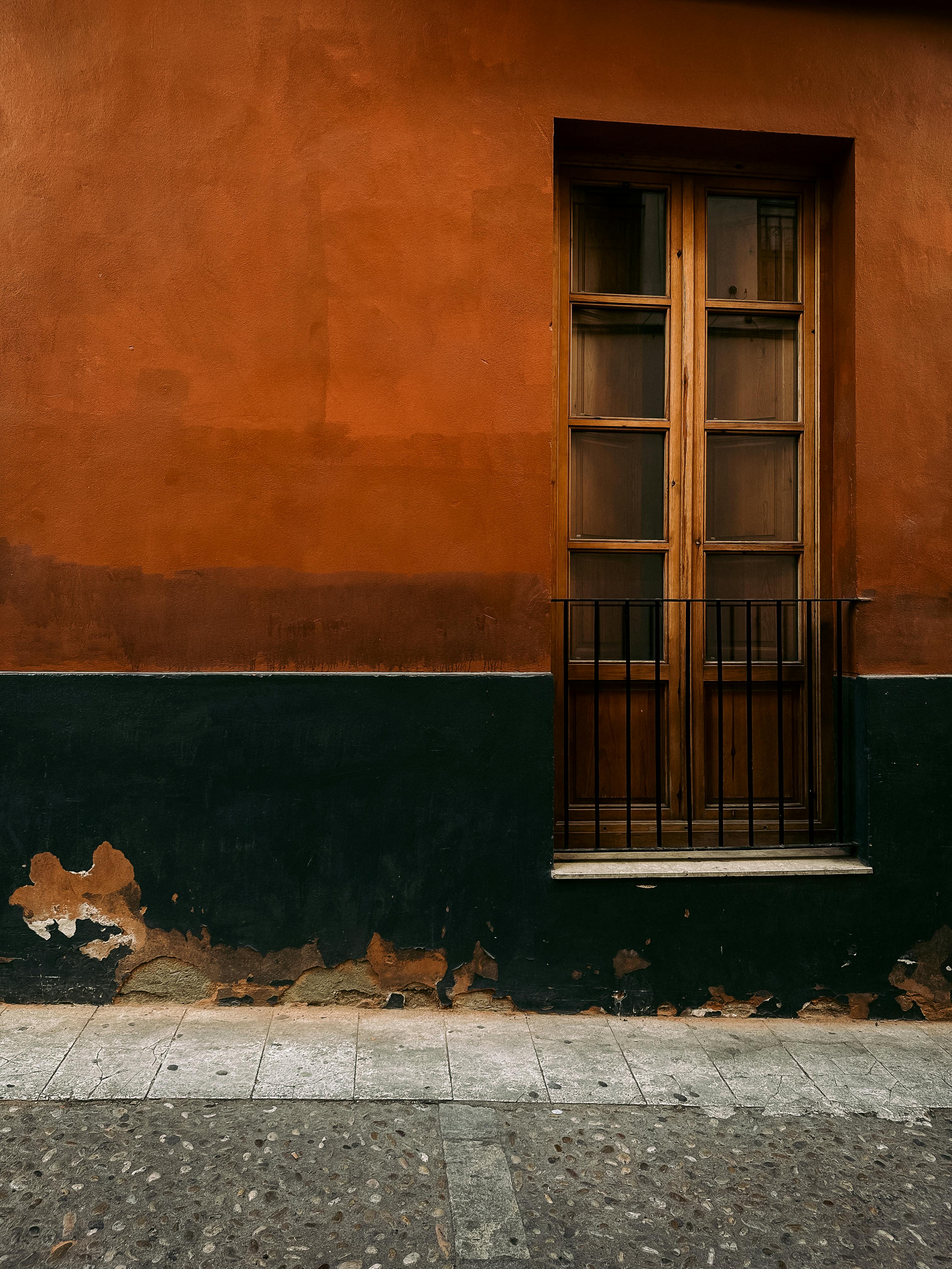 Zadarmo Zvetrané drevené dvere zasadené do textúrovanej oranžovej steny vo Valencii v Španielsku. Fotka z fotobanky