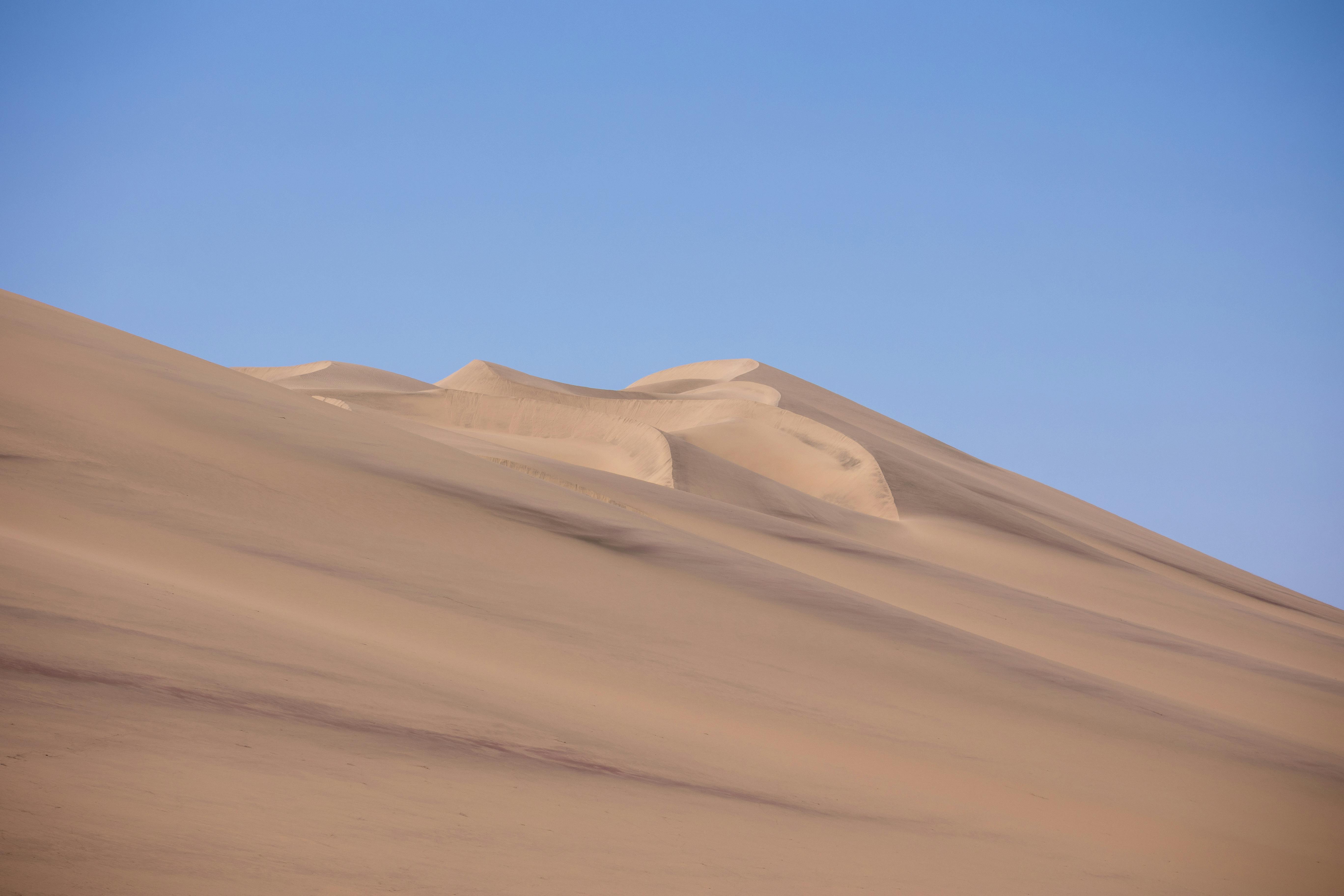 grátis Dunas de areia serenas na Namíbia, capturadas pela luz natural sob um céu azul límpido. Foto profissional