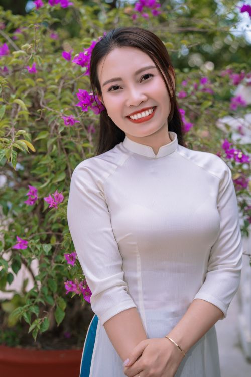Free Joyful woman in traditional dress standing in a garden with vibrant purple flowers. Stock Photo