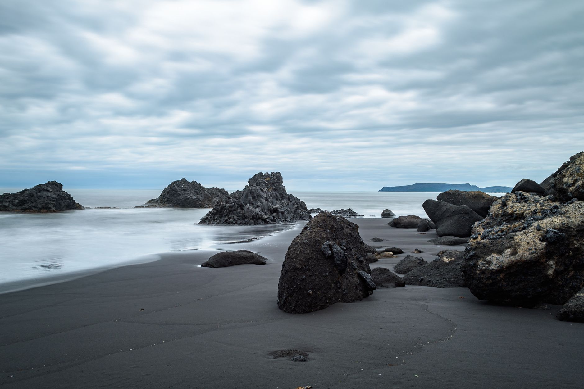 Calm ocean waves on a black sand beach with volcanic rocks under a cloudy sky.. pexels, calm, ocean