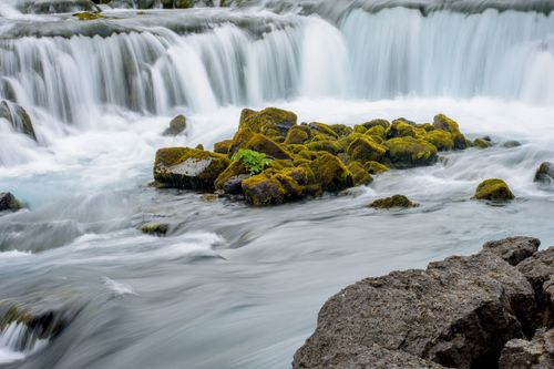 Free A tranquil waterfall cascading over moss-covered rocks, creating a serene and natural landscape. Stock Photo