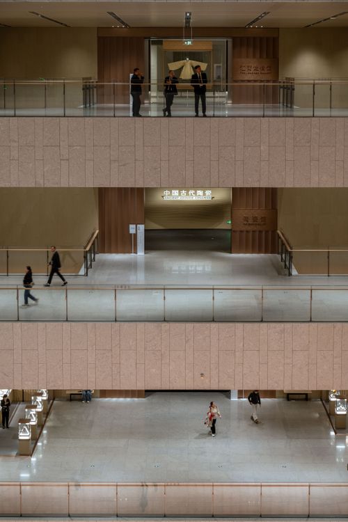 Free View of a multi-level building interior with people walking on different floors, creating a minimalist architectural scene. Stock Photo