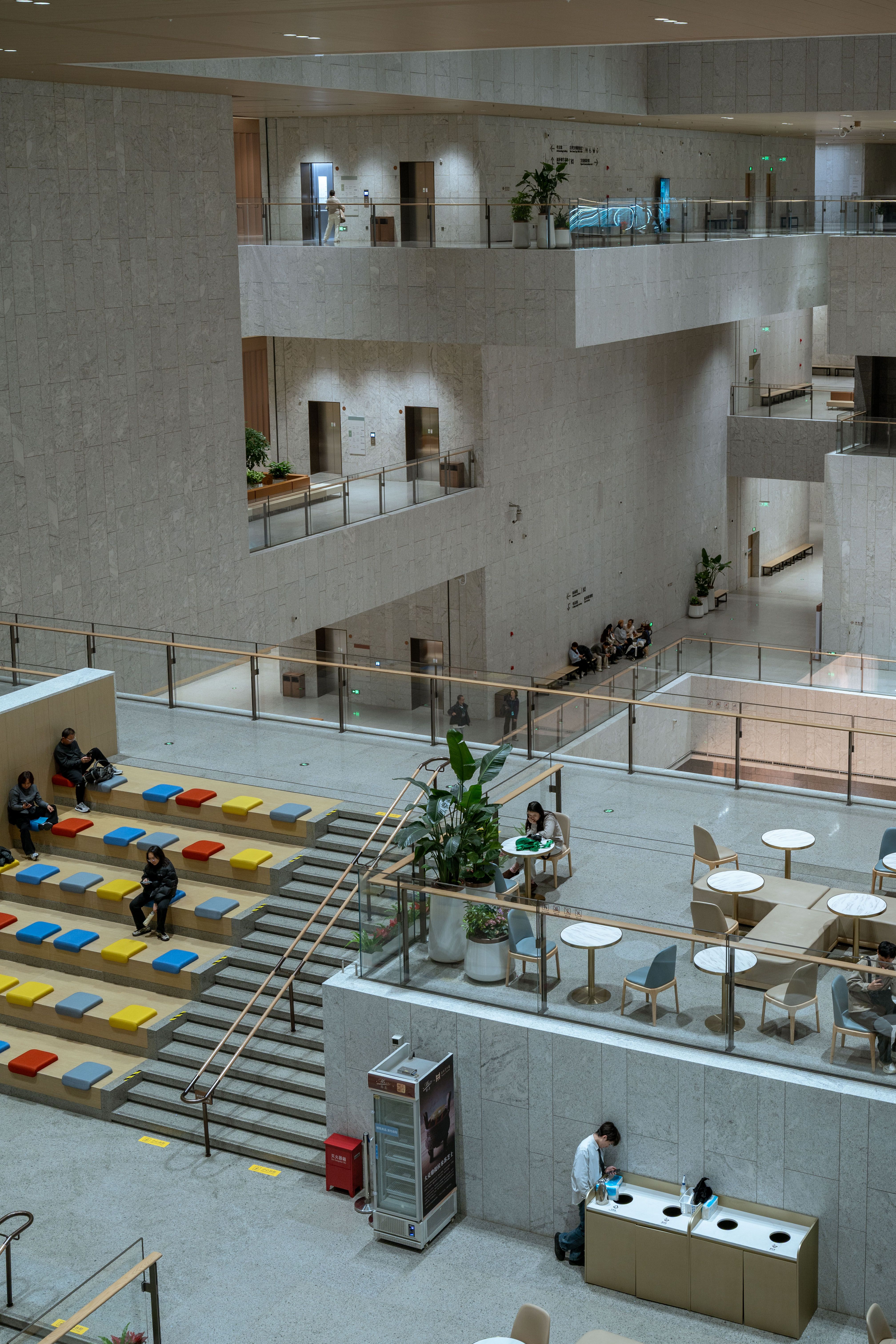 This image captures a modern, multi-level interior public space with seating and people.