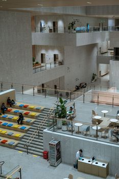 This image captures a modern, multi-level interior public space with seating and people.