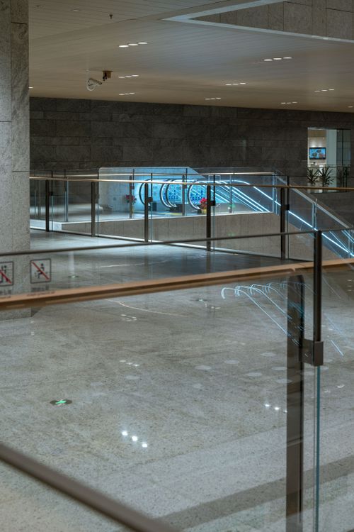 Free Spacious interior of a modern shopping mall with a sleek escalator and reflective marble floors. Stock Photo