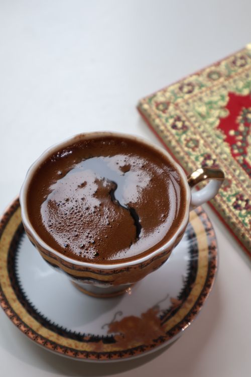 Free Top view of Turkish coffee in a decorative cup and saucer beside an ornate textile. Stock Photo