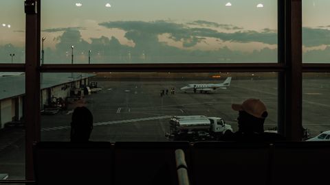 A scenic view from an airport terminal overlooking an airplane on the tarmac during twilight.