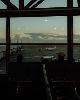 A scenic view from an airport terminal overlooking an airplane on the tarmac during twilight.