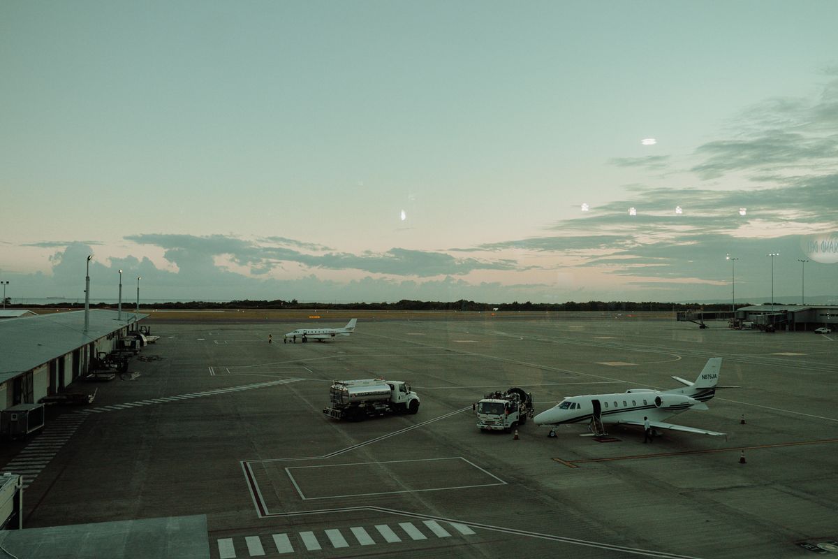 Private jets and ground service vehicles on an airport tarmac