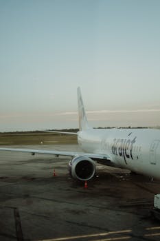 A commercial airplane parked at an airport terminal during the day, ready for departure.