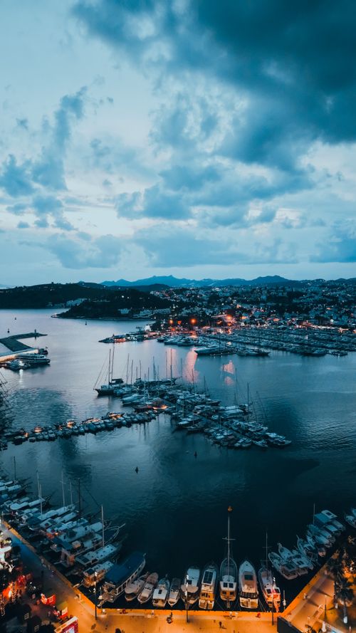 Free Stunning aerial shot of Bodrum harbor at twilight, showcasing yachts and city lights against a serene blue sky. Stock Photo