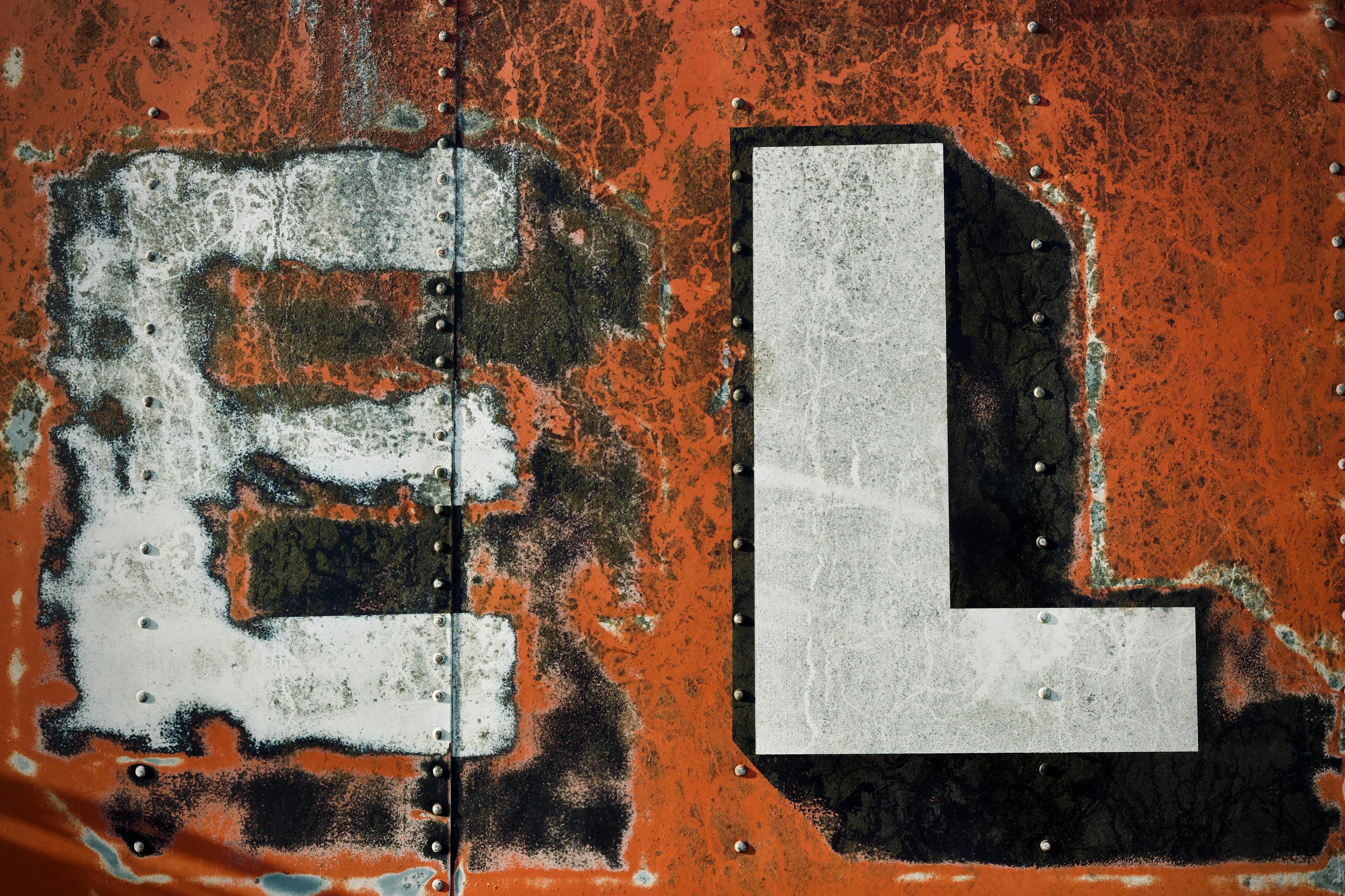 grátis Visão detalhada da superfície metálica desgastada e enferrujada, com letras e parafusos brancos. Foto profissional