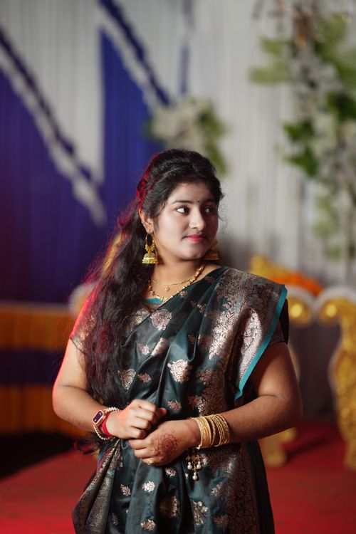 Free Young woman wearing traditional Indian attire posing gracefully indoors against a decorative backdrop. Stock Photo