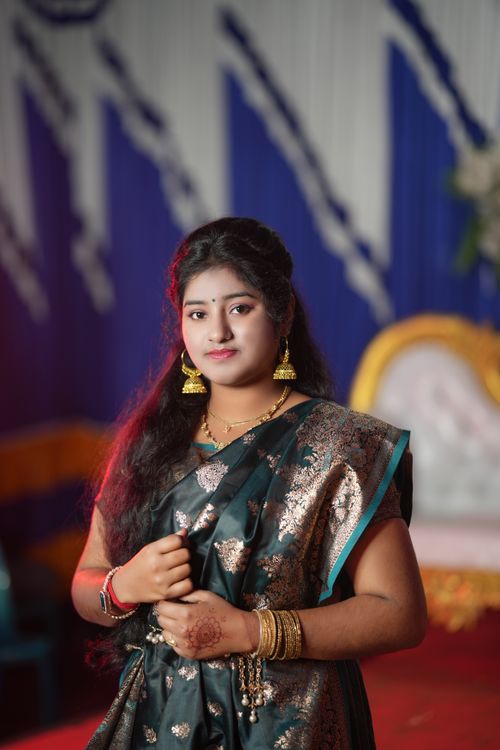 Free Portrait of an Indian woman in traditional saree and jewelry at a festive event indoors. Stock Photo