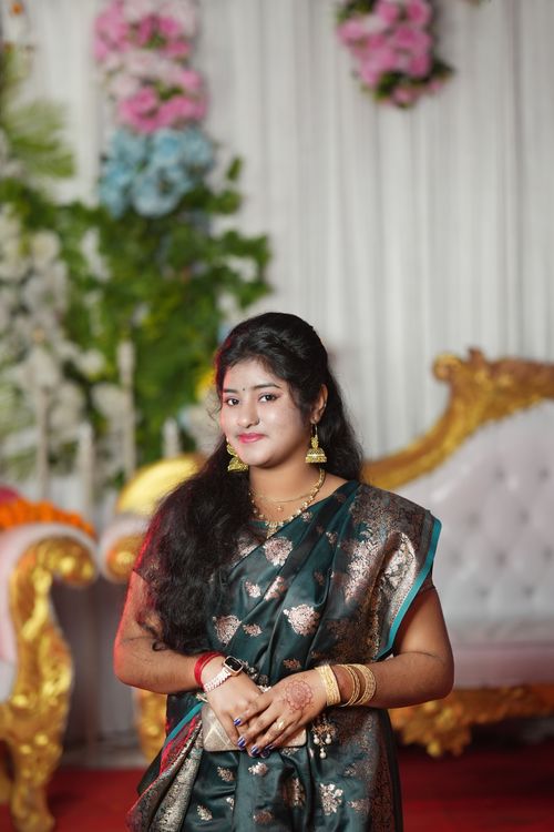 Free Portrait of a woman in traditional attire at a lavish indoor event, with a backdrop of floral decor. Stock Photo