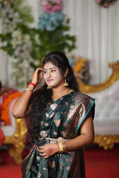 Free An elegant woman in a beautiful saree attends a cultural event, showcasing traditional Indian fashion with jewelry. Stock Photo