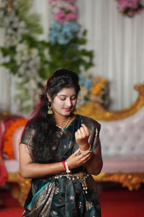 Free A young woman in traditional Indian clothing, standing gracefully indoors, reminiscent of a festive celebration. Stock Photo